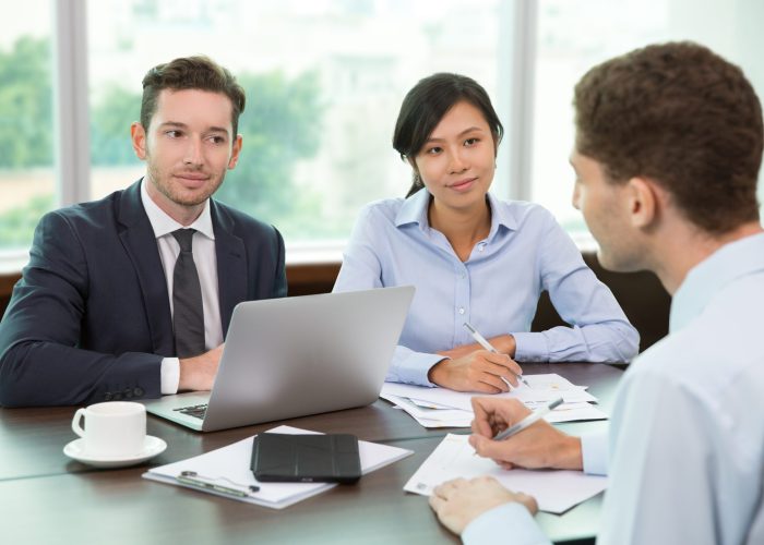 Group of business people holding meeting in office. Two business people listening to their colleague. Teamwork concept